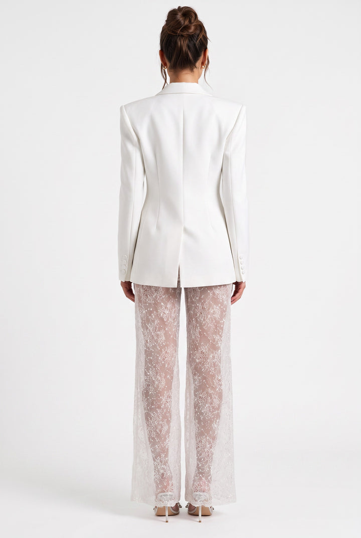 Back view of a lily ivory tailored blazer paired with sheer lace wide-leg trousers on a model