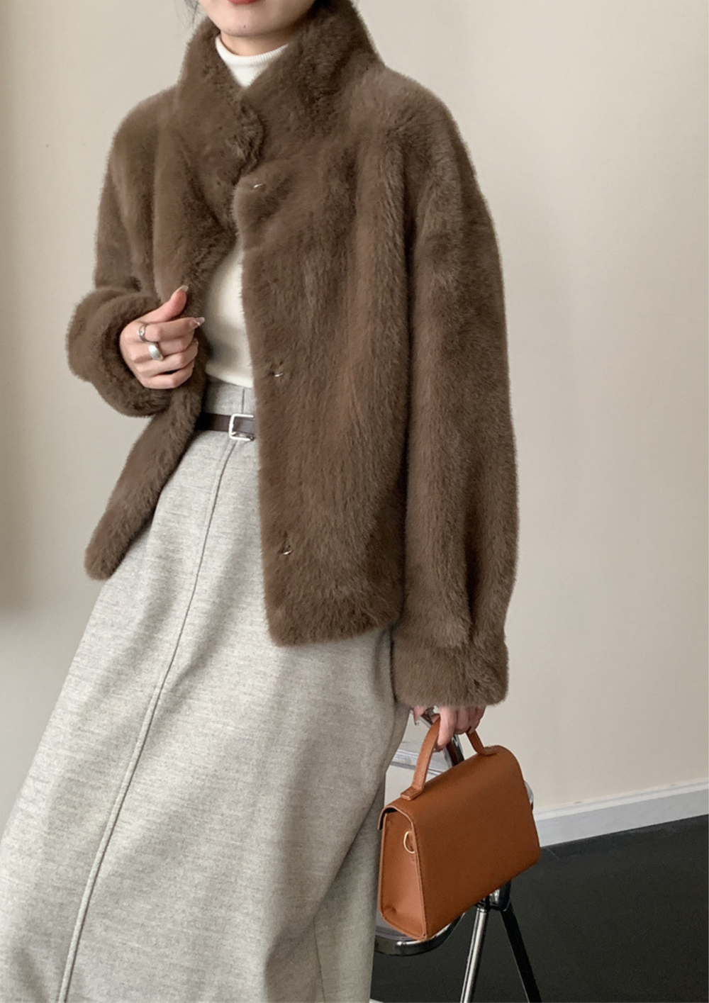 lily Mila plush brown mink fur coat with a stand collar, worn over a white turtleneck and grey skirt.