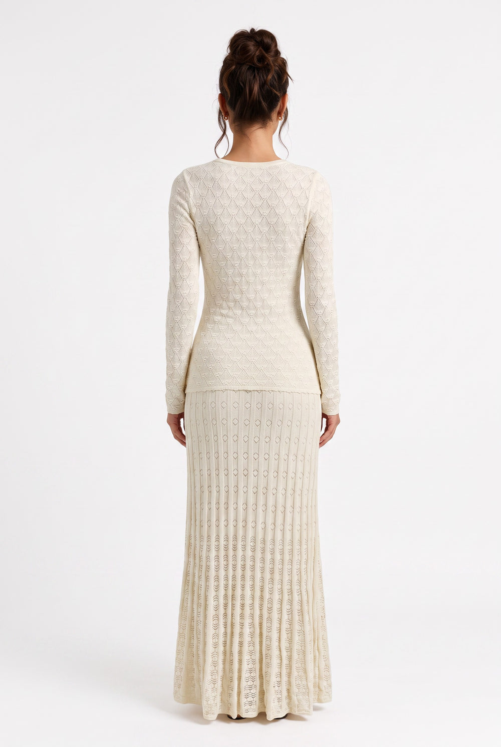 Back view of a lily Mirella cream crochet knit maxi dress with long sleeves and a flared hem on a model