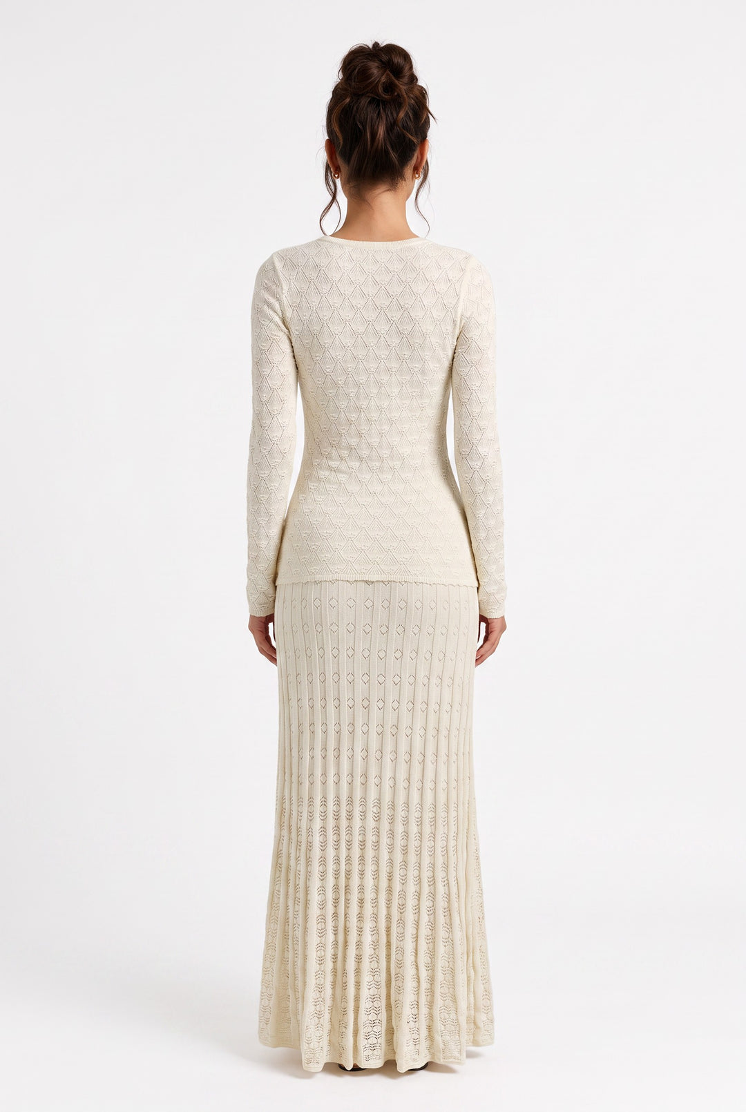 Back view of a lily Mirella cream crochet knit maxi dress with long sleeves and a flared hem on a model